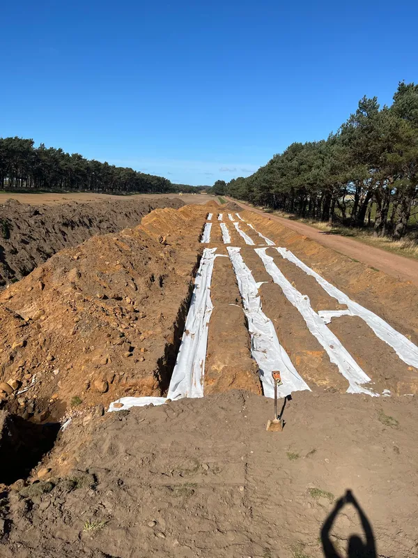 Gravel-filled land drainage runs cut across a field