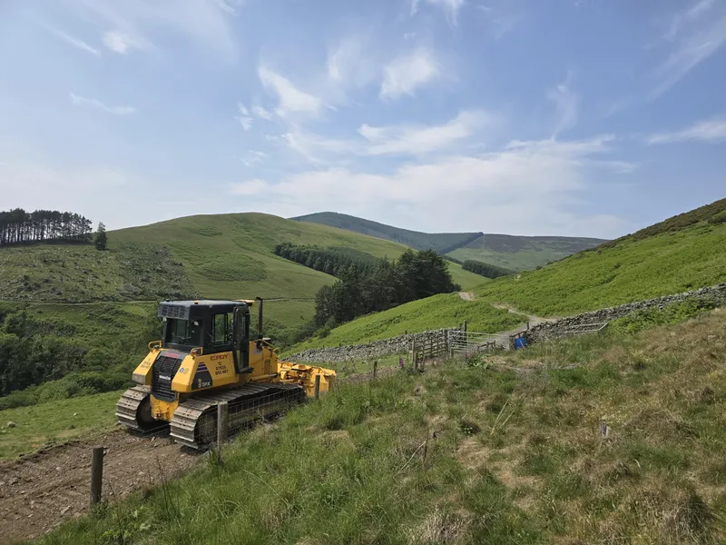 Dozer cutting a hill road through a glen