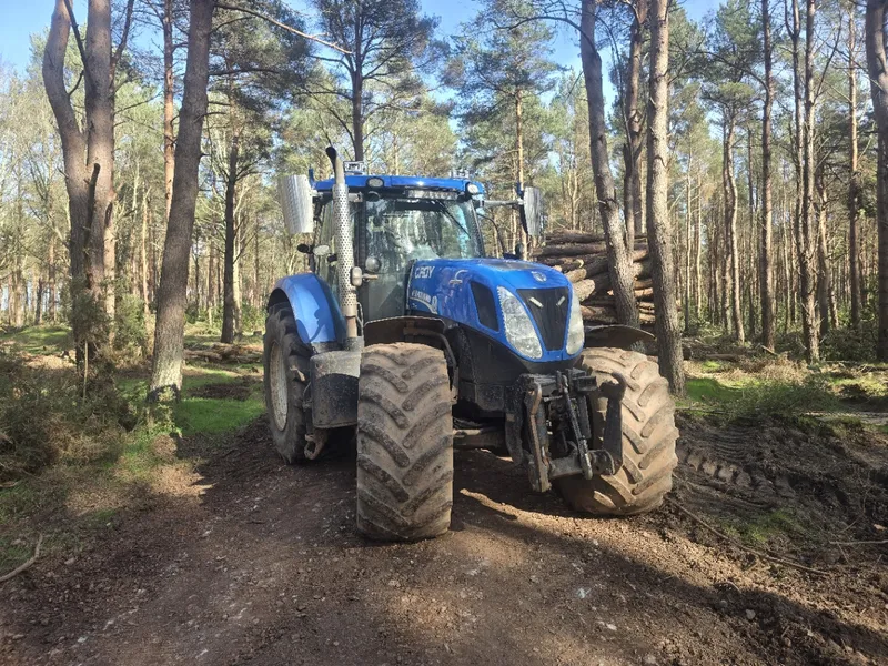 New Holland tractor working among trees on a forestry job